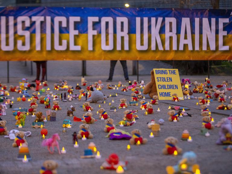 Die Abbildung zeigt eine symbolische Aktion unter der Leitung von Avaaz-Mitgliedern und ukrainischen Flüchtlingen mit der Hinterlegung Tausender Teddybären und Spielzeugen als Symbol für die Tausenden Kinder, die im Krieg in der Ukraine entführt wurden.