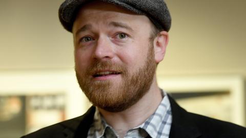 Portrait des Illustrators Torben Kuhlmann, der eine Schiebermütze trägt und freundlich in die Kamera schaut