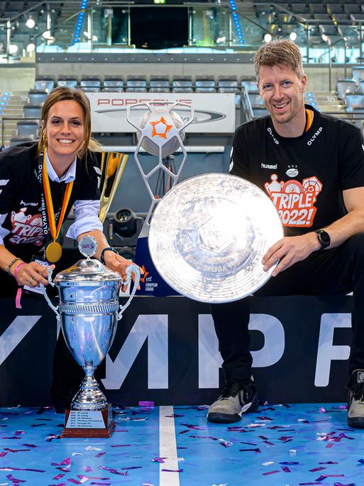 Lena Backhaus (l.), Geschäftsführerin der Handball-Frauen der SG BBM Bietigheim, posiert mit Trainer Markus Gaugisch mit dem Triple.