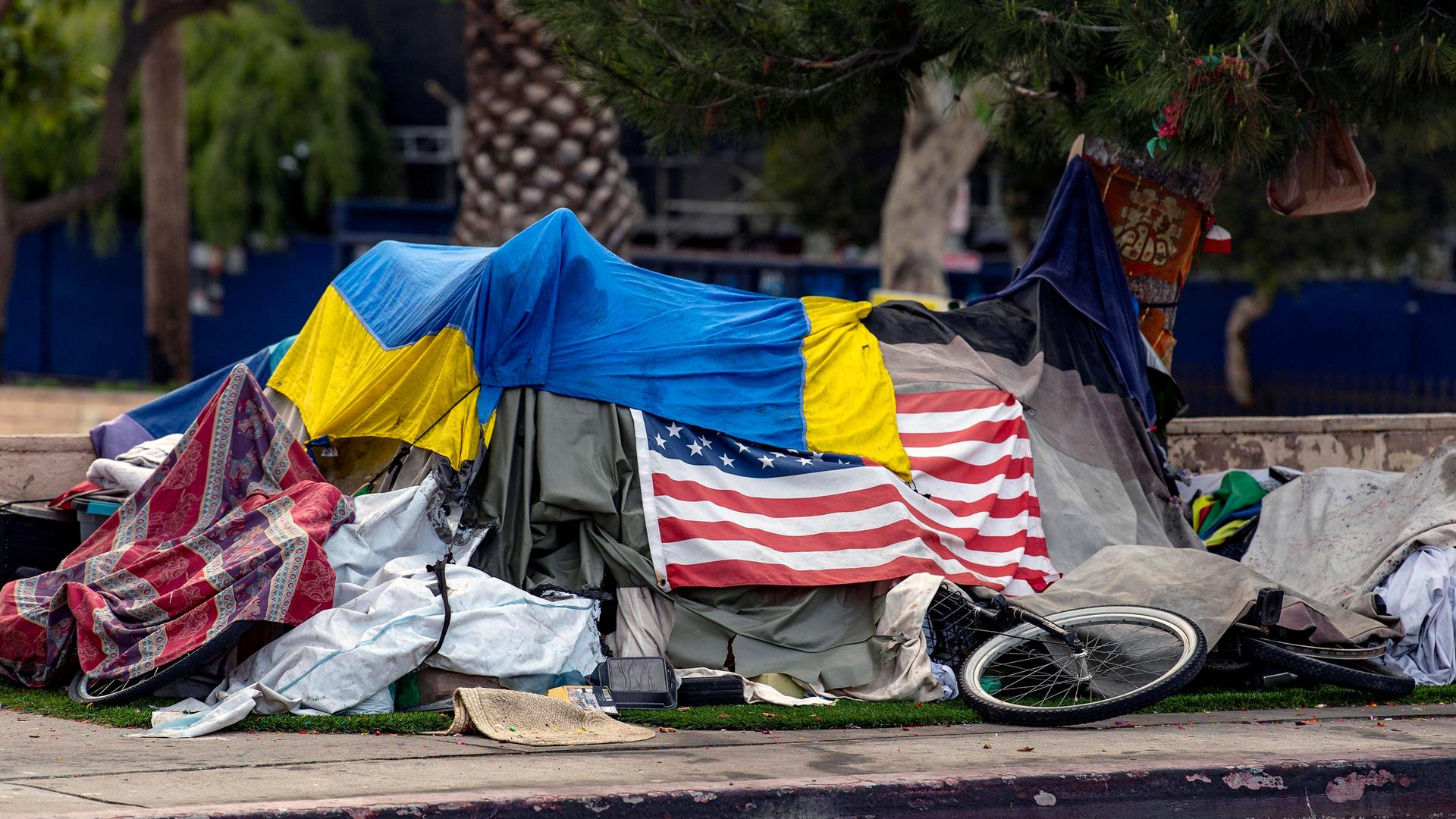 Das Zelt eines Obdachlosen am Straßenrand ist mit der amerikanischen und der ukrainischen Flagge bedeckt.