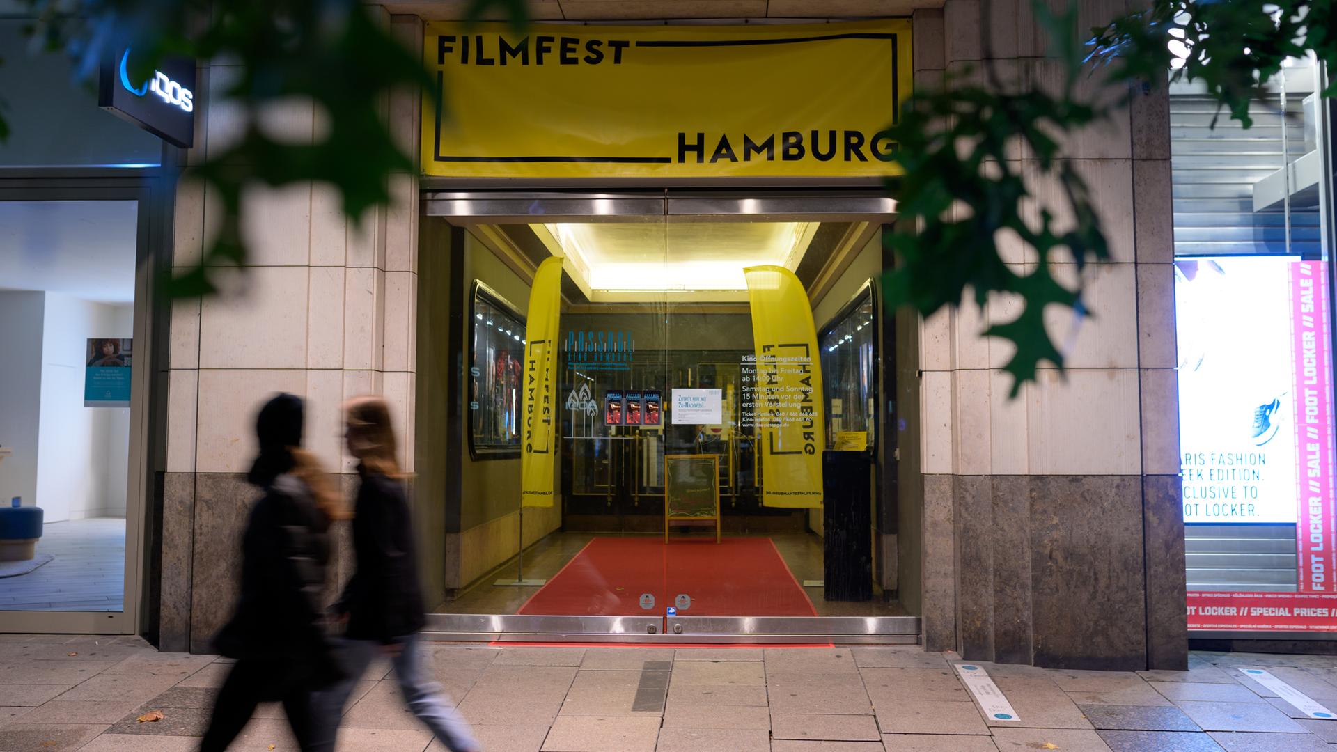 Zwei Frauen gehen vor dem Passage-Kino in der Mönckebergstraße vorbei, wo mit Plakaten auf das "Filmfest Hamburg" hingewiesen wird.