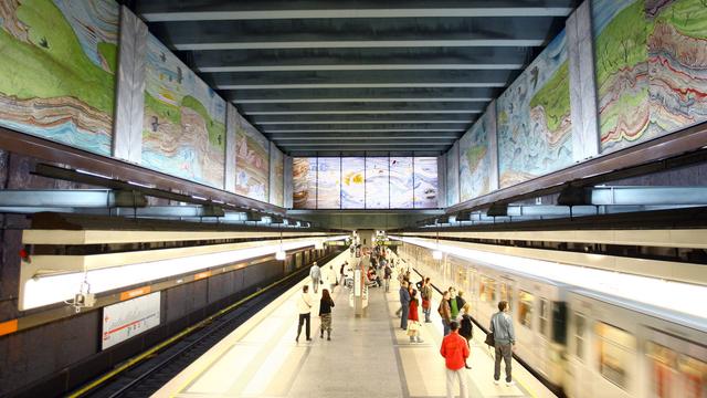 Einfahrender Zug in der U-Bahnstation Volkstheater in Wien. Am oberen Teil des Bildes sind die Wandgemälde ich der Station zu sehen.