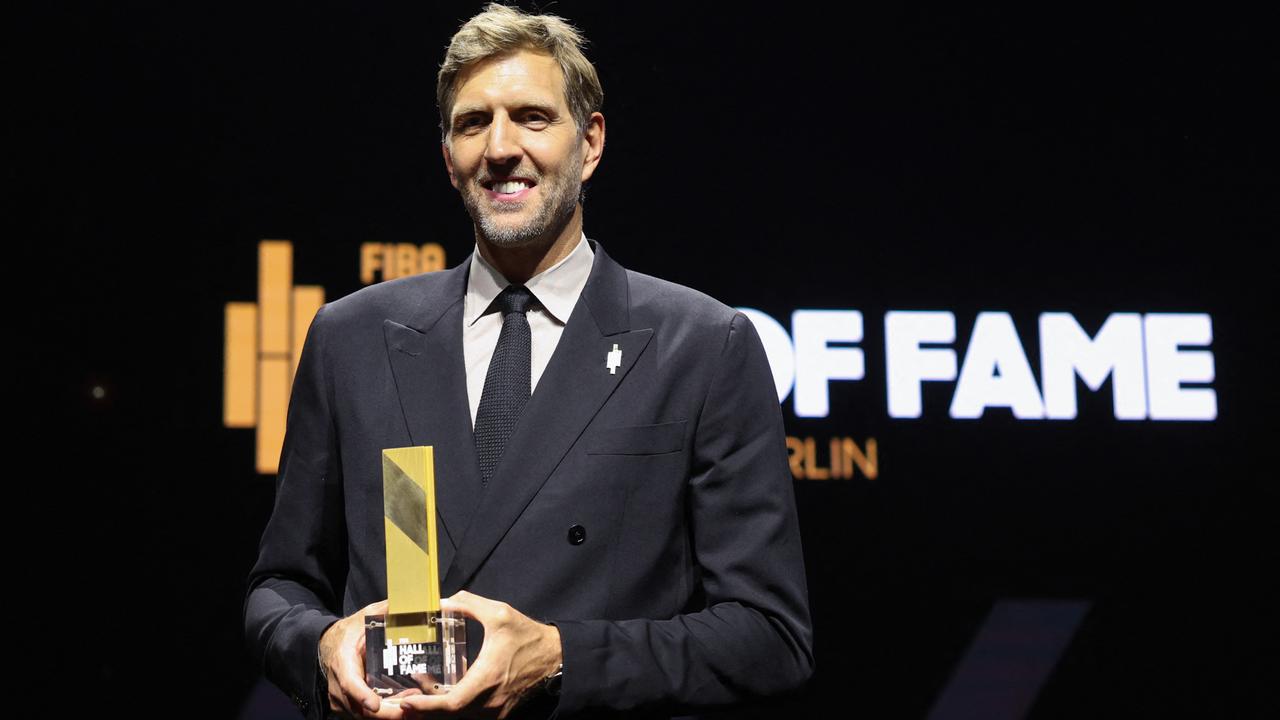 Dirk Nowitzki steht im dunkelgrauen Anzug mit einer goldfarbenen Trophäe vor dem Schriftzug "Hall of Fame".