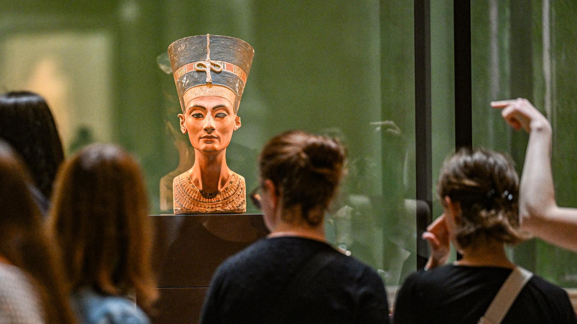 Die Büste der Nofretete wird von Besuchern und Besucherinnen im Museum in Berlin betrachtet