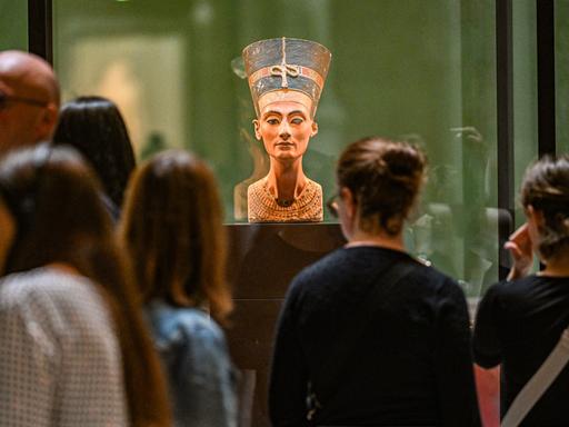 Die Büste der Nofretete wird von Besuchern und Besucherinnen im Museum in Berlin betrachtet