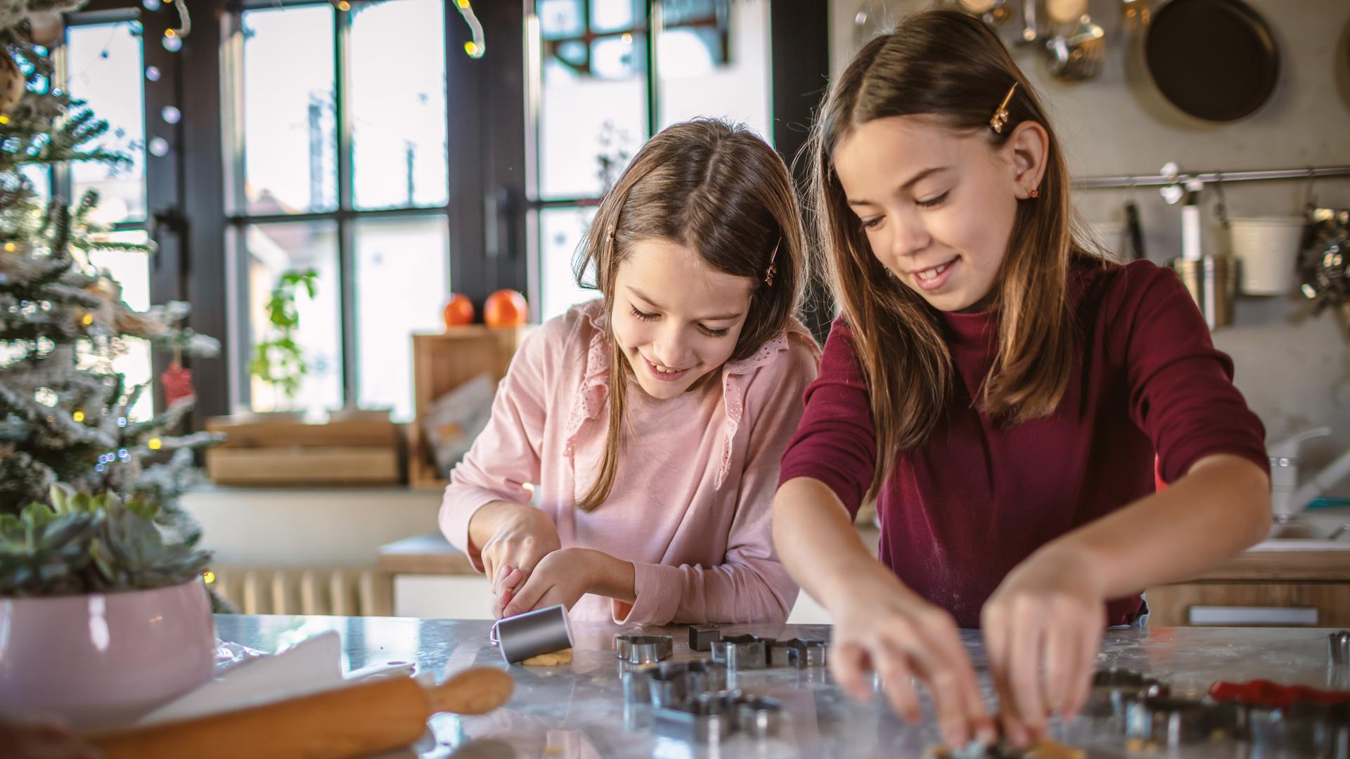 zwei Mädchen in der Küche beim Plätzchenausstechen zwei Mädchen in der Küche beim Plätzchenausstechen