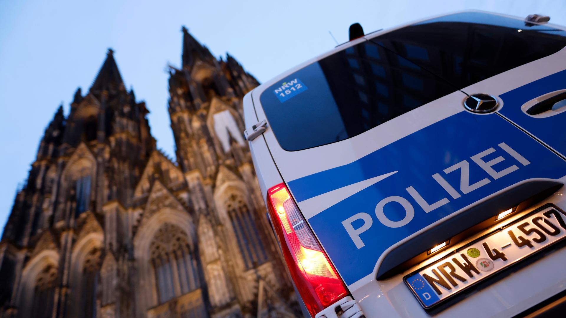 Ein Polizeiautor steht vor dem Kölner Dom