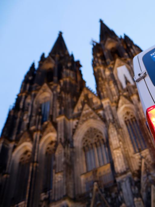 Ein Polizeiautor steht vor dem Kölner Dom