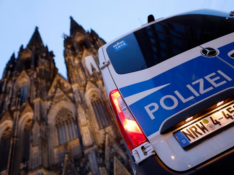 Ein Polizeiautor steht vor dem Kölner Dom