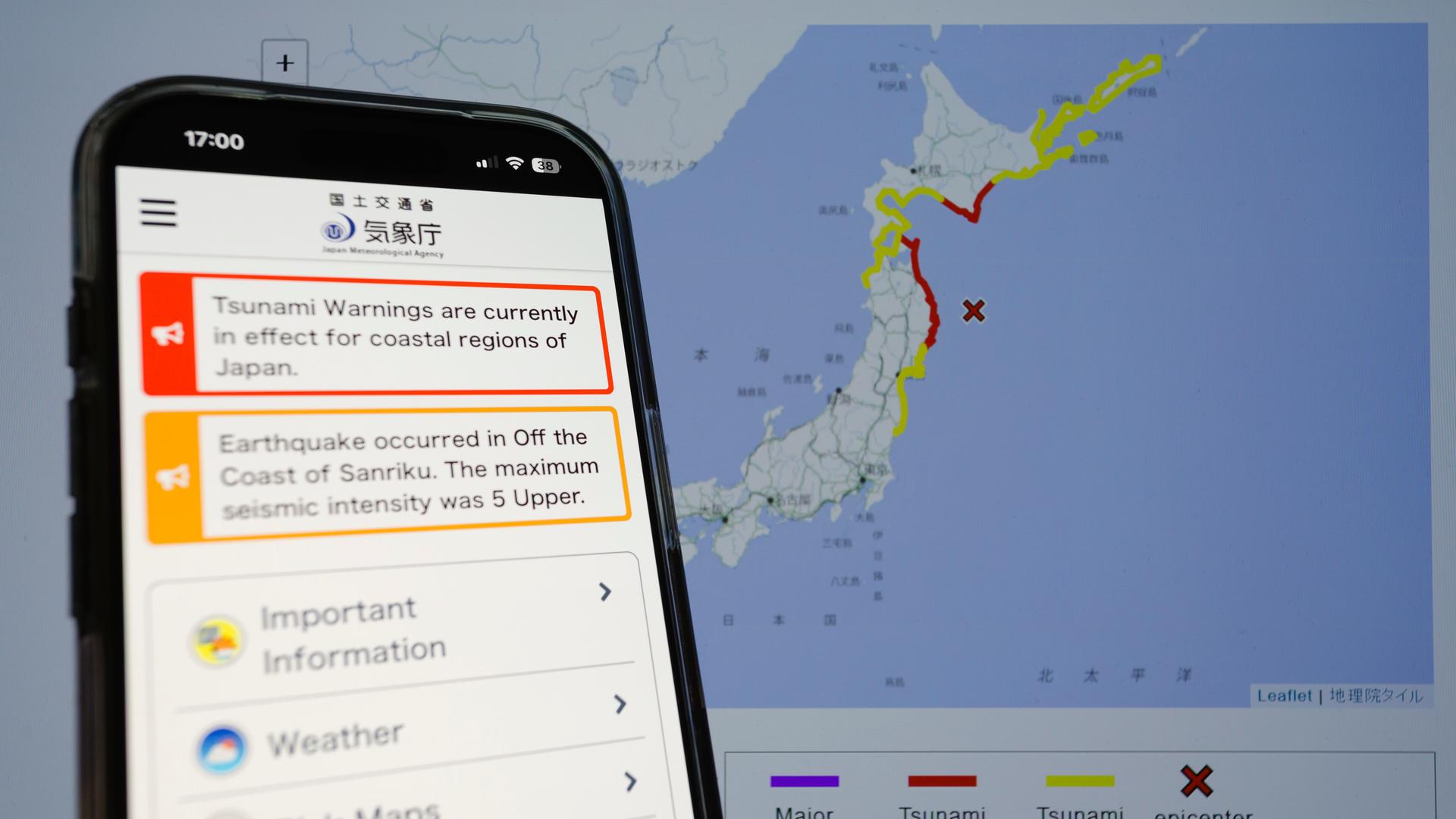 Auf einem Smartphone ist mit einer von der Behörde herausgegebenen Tsunamiwarnungskarte im Hintergrund zu sehen.