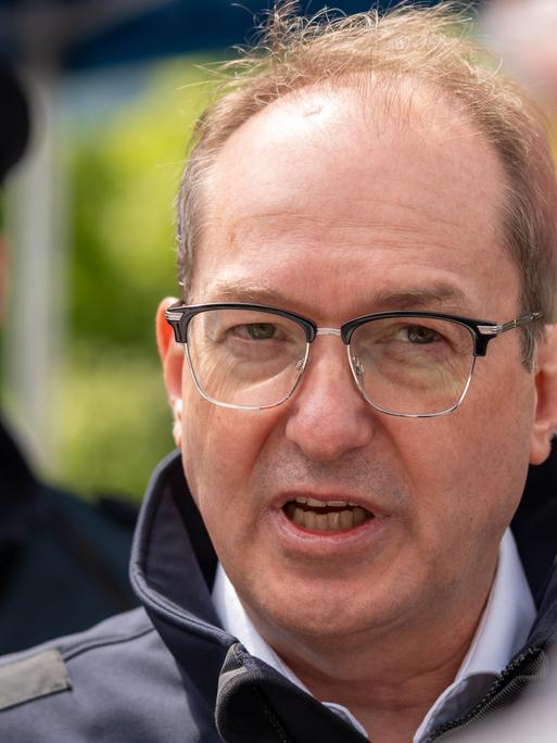 Bundesinnenminister Alexander Dobrindt (CSU) steht bei einem Besuch auf der Autobahn A93 zwischen Deutschland und Österreich vor Presseleuten und spricht.