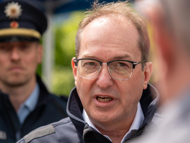 Bundesinnenminister Alexander Dobrindt (CSU) steht bei einem Besuch auf der Autobahn A93 zwischen Deutschland und Österreich vor Presseleuten und spricht.