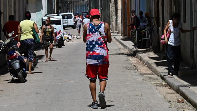 Ein Mann in einem T-Shirt mit der US-Flagge geht durch eine Straße in Havanna. Er ist von hinten nicht zu erkennen.