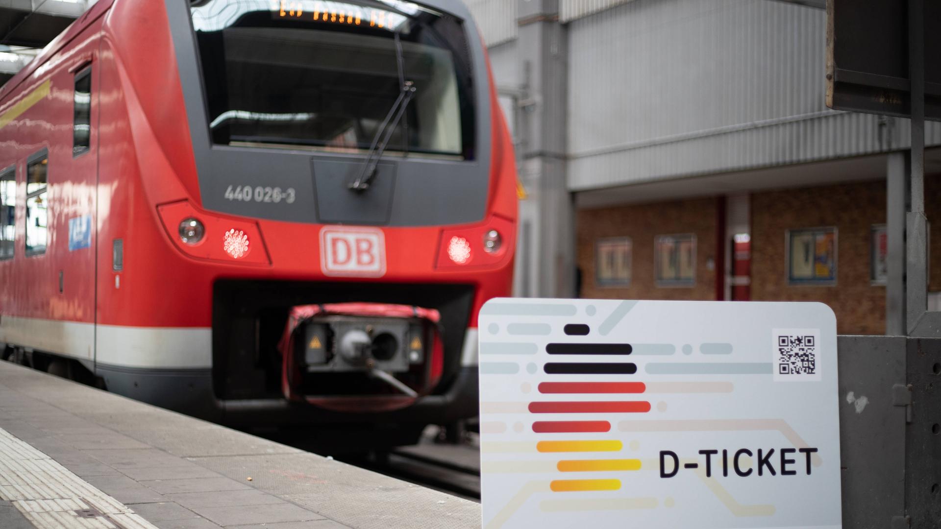 Das Deutschland-Ticket vor einer roten Regionalbahn.