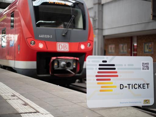 Das Deutschland-Ticket vor einer roten Regionalbahn.