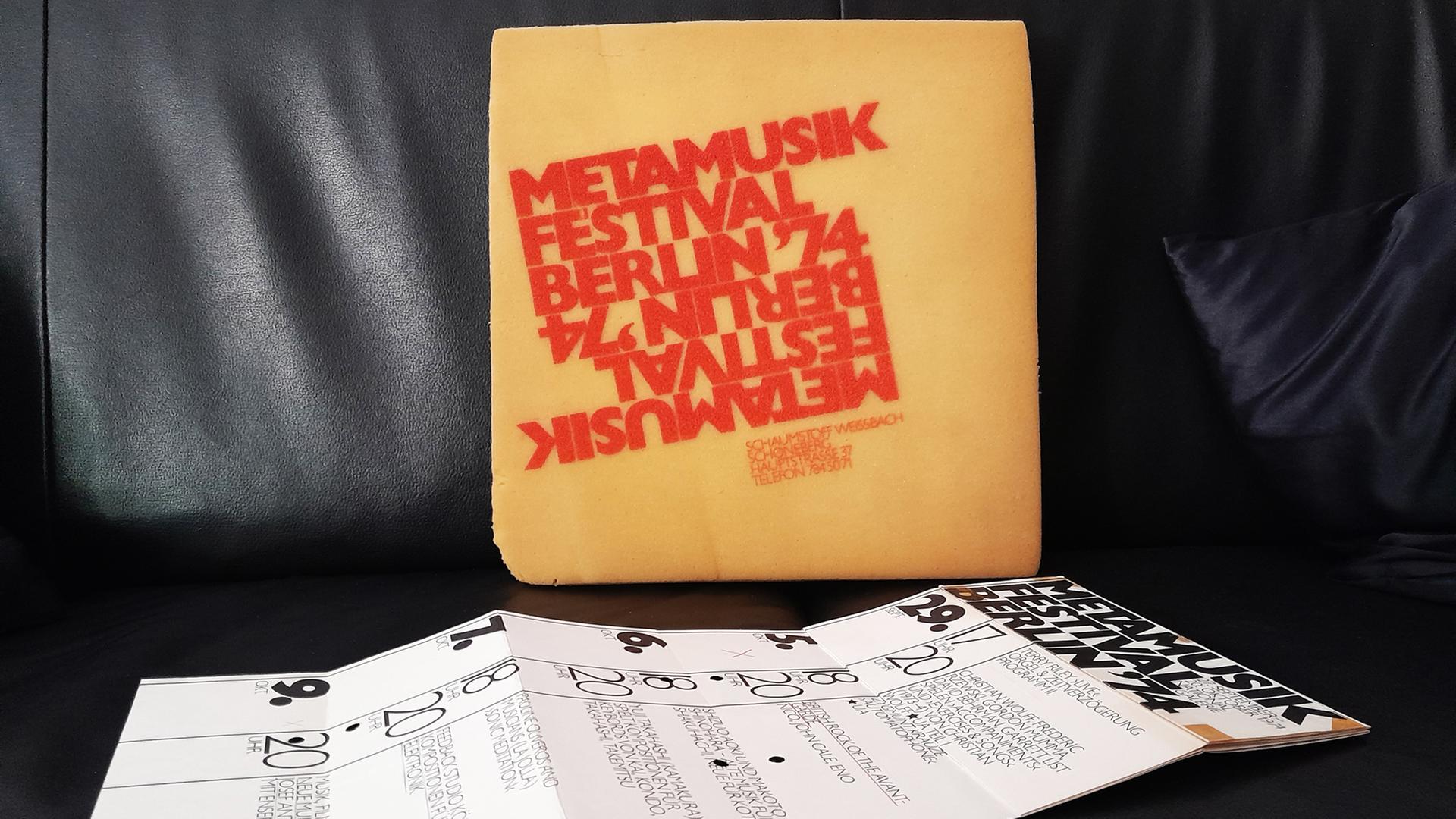 Ein mit roten Buchstaben bedrucktes Sitzkissen und ein entfalteter Flyer liegen auf einem schwarzen Ledersitz Ein mit roten Buchstaben bedrucktes Sitzkissen und ein entfalteter Flyer liegen auf einem schwarzen Ledersitz