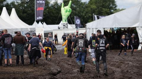 Wacken: Metal-Fans gehen über das schlammige Festivalgelände. 