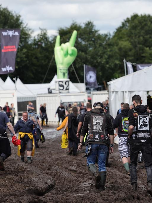 Wacken: Metal-Fans gehen über das schlammige Festivalgelände. 