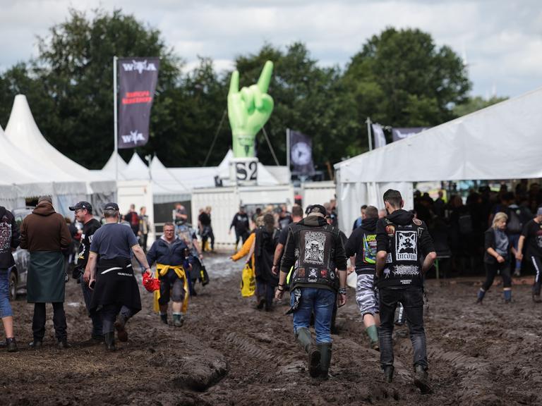 Wacken: Metal-Fans gehen über das schlammige Festivalgelände. 