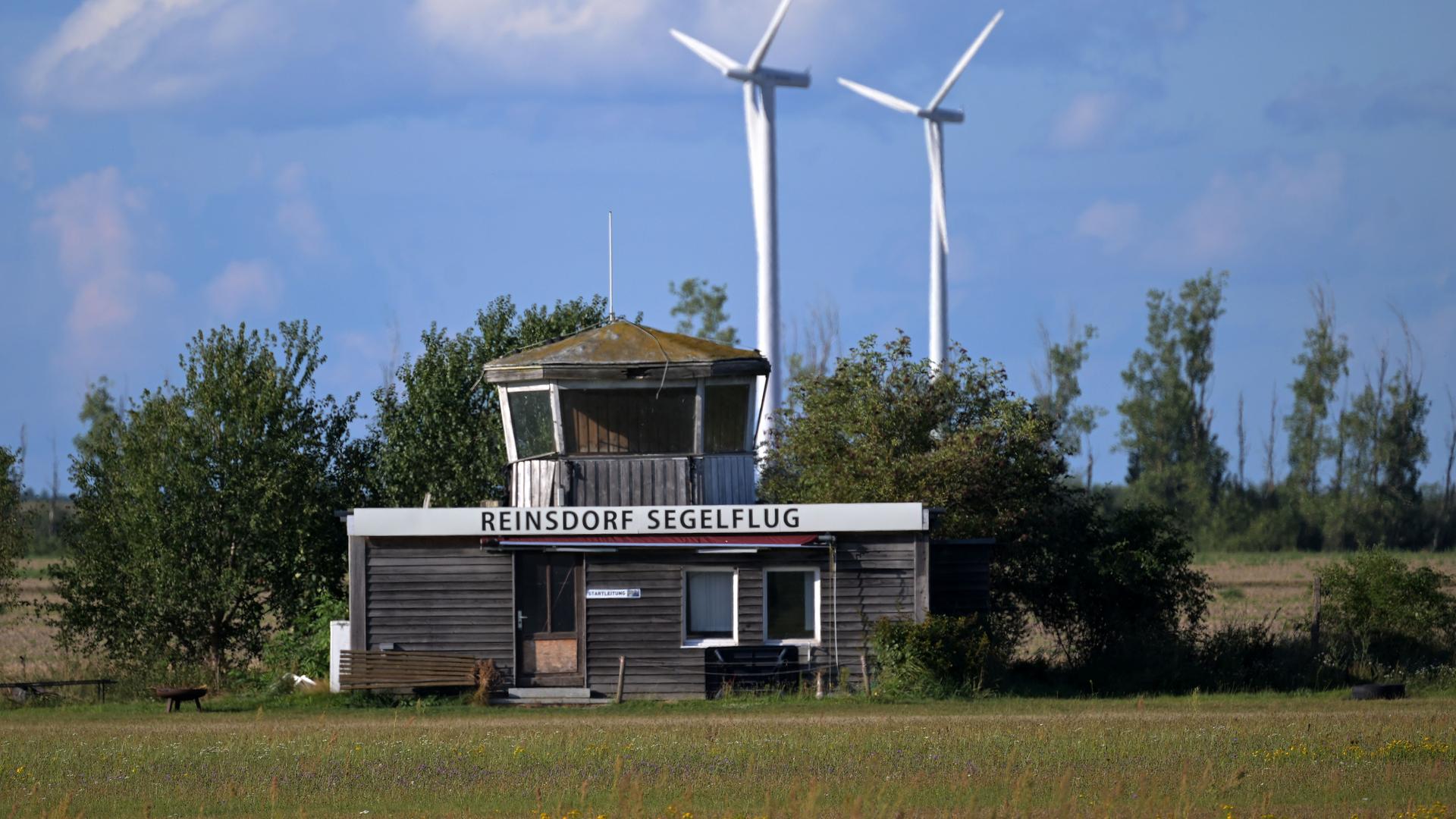 Ein alter Tower steht auf dem Flugplatz Reinsdorf. Der Flugplatz wird von Kleinflugzeugen genutzt. Im Hintergrund stehen zwei Windräder.