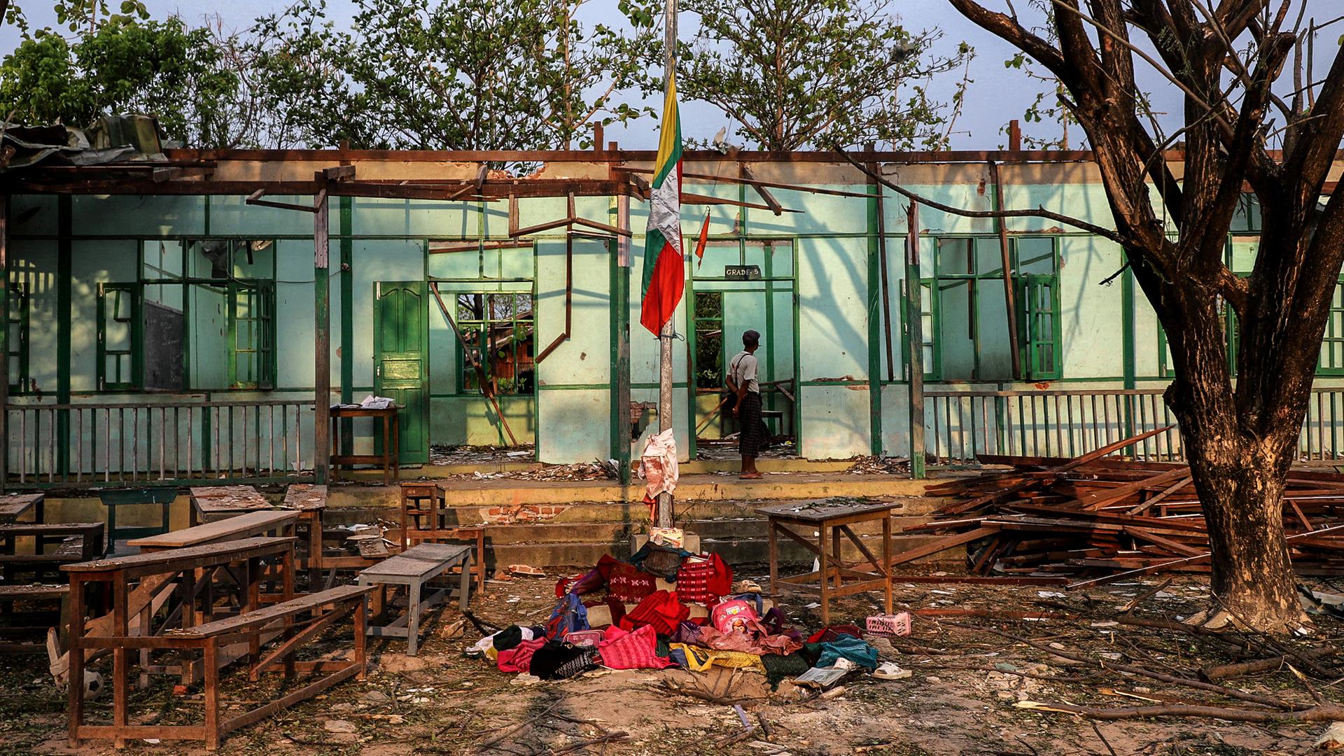 Blick in das zerstörte Schulgebäude in Myanmar. Davor liegen auf einem Haufen Schulranzen und Kleidungsstücke von Kindern.