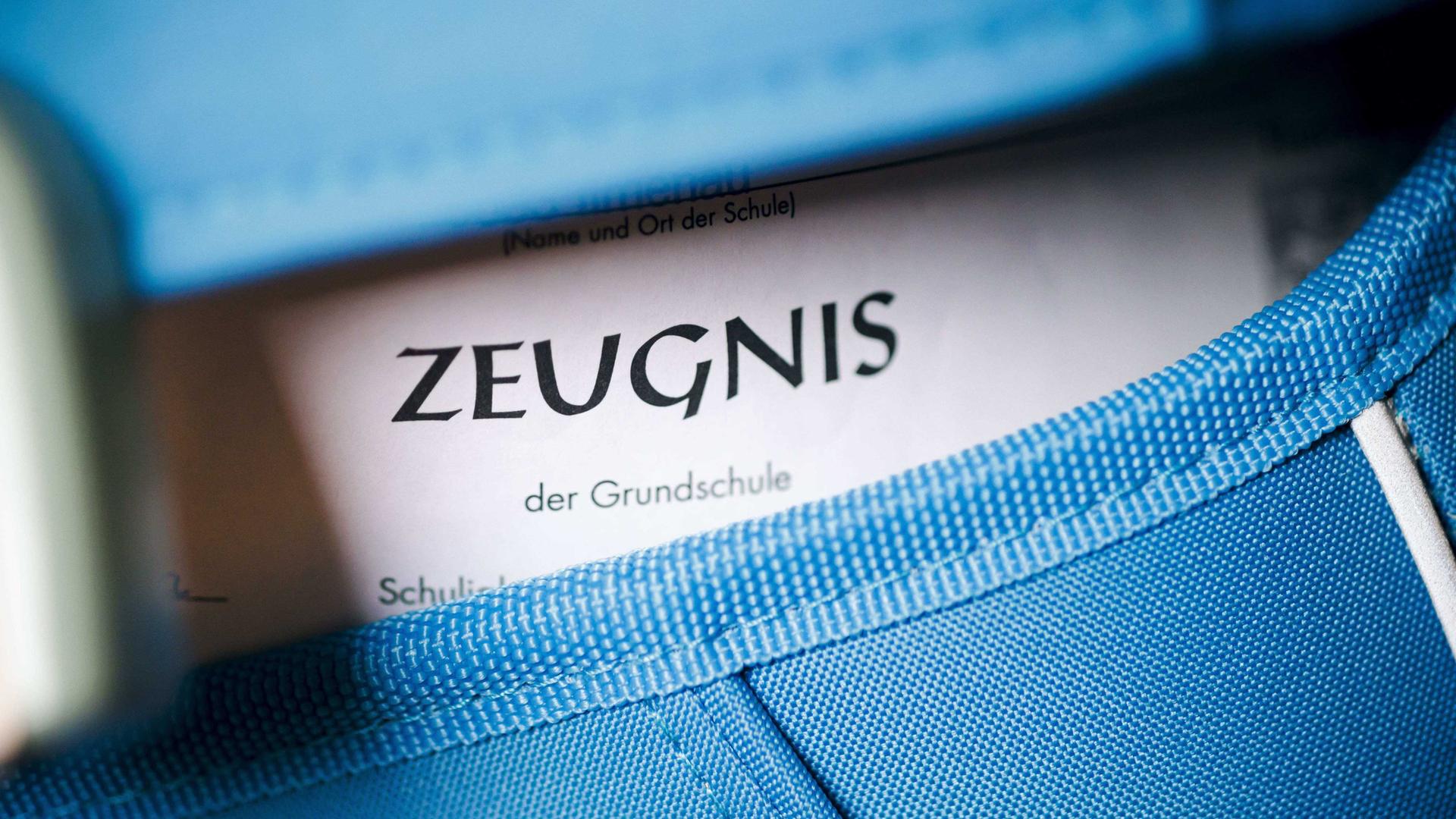 Nahaufnahme eines blauen Schulranzens, aus dem ein Zeugnis guckt. Nahaufnahme eines blauen Schulranzens, aus dem ein Zeugnis guckt.