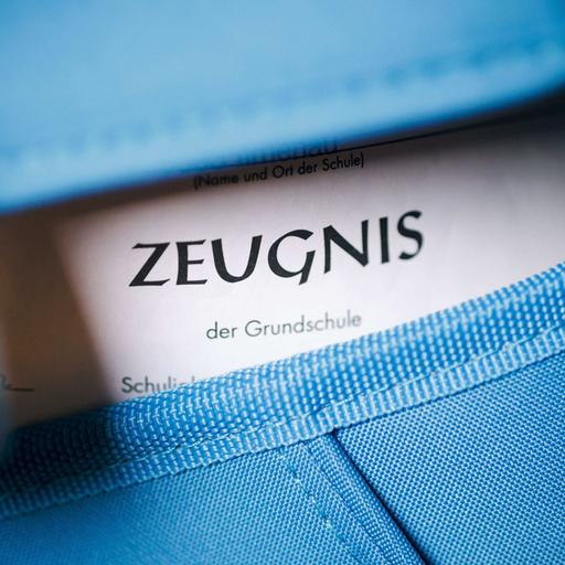 Nahaufnahme eines blauen Schulranzens, aus dem ein Zeugnis guckt.