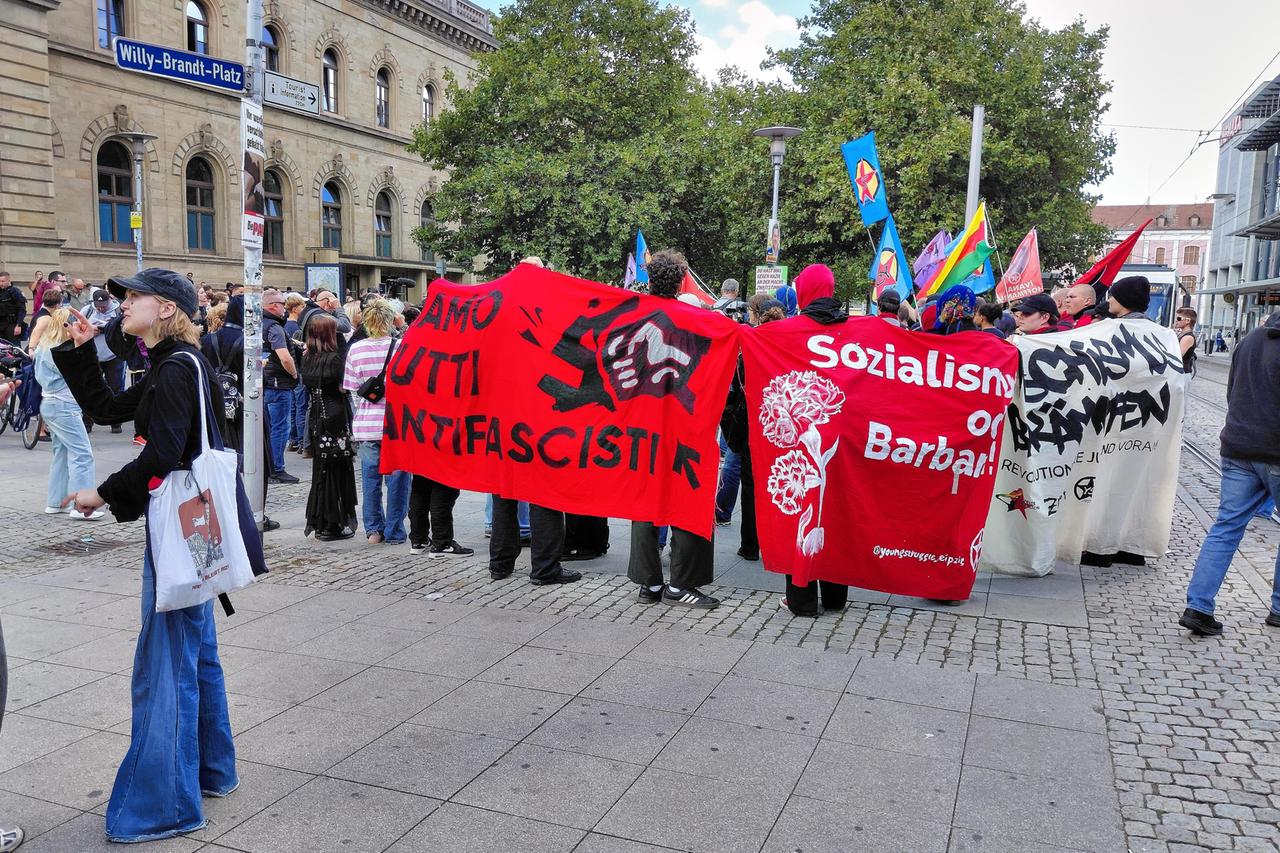 Dutzende Demonstranten haben sich vor dem Hauptbahnhof in Magdeburg versammelt. Viele tragen Banner aus dem linksextremen Milieu.