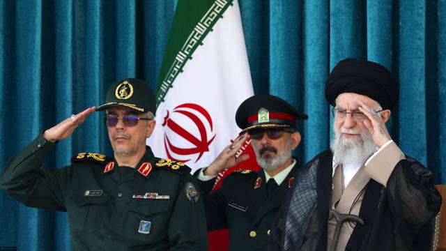 Irans oberster geistlicher Führer Ajatollah Ali Chamenei sitzt neben zwei Militärangehörigen