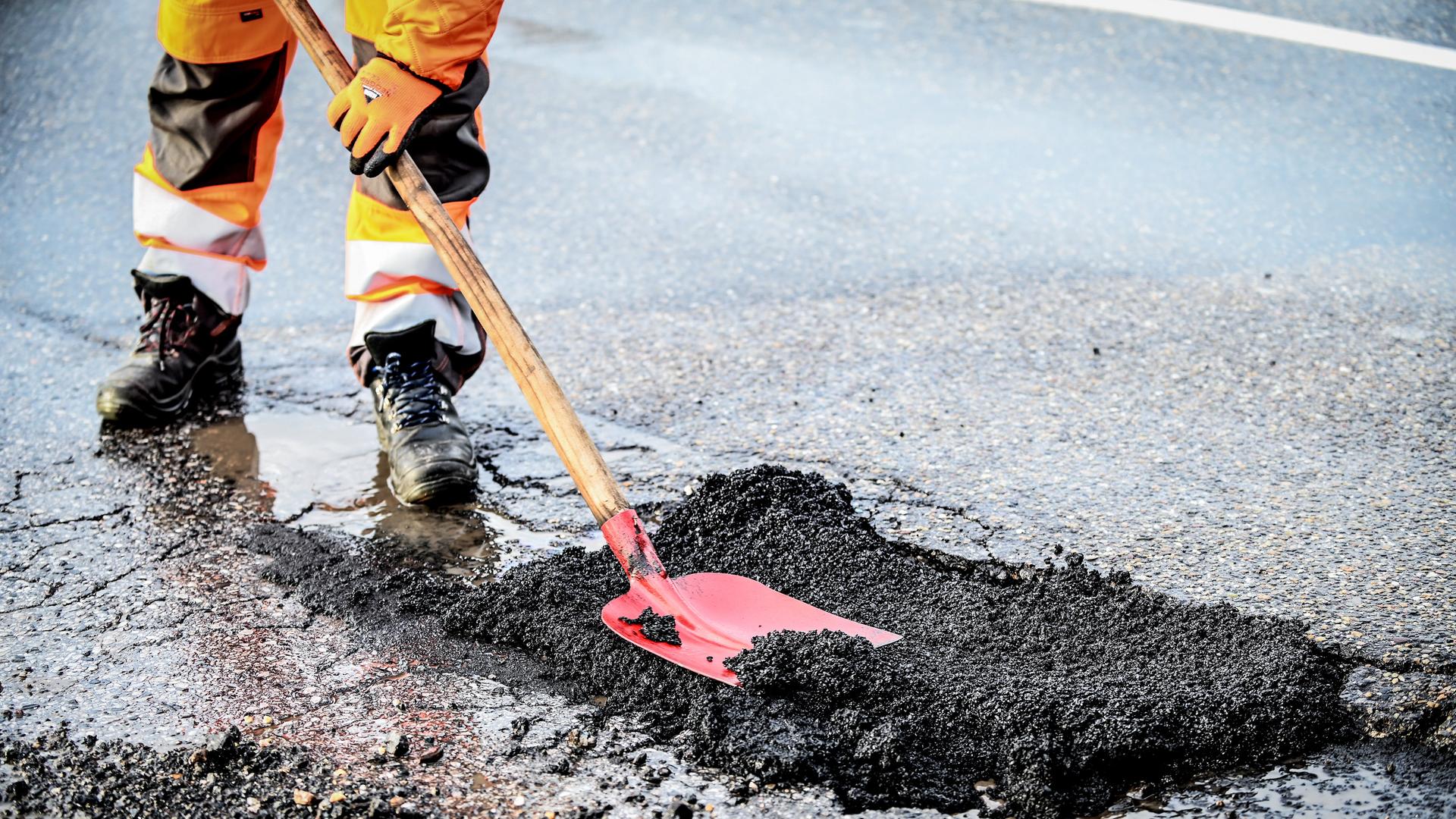 Ein Straßenbauarbeiter erneuert den Asphalt.
