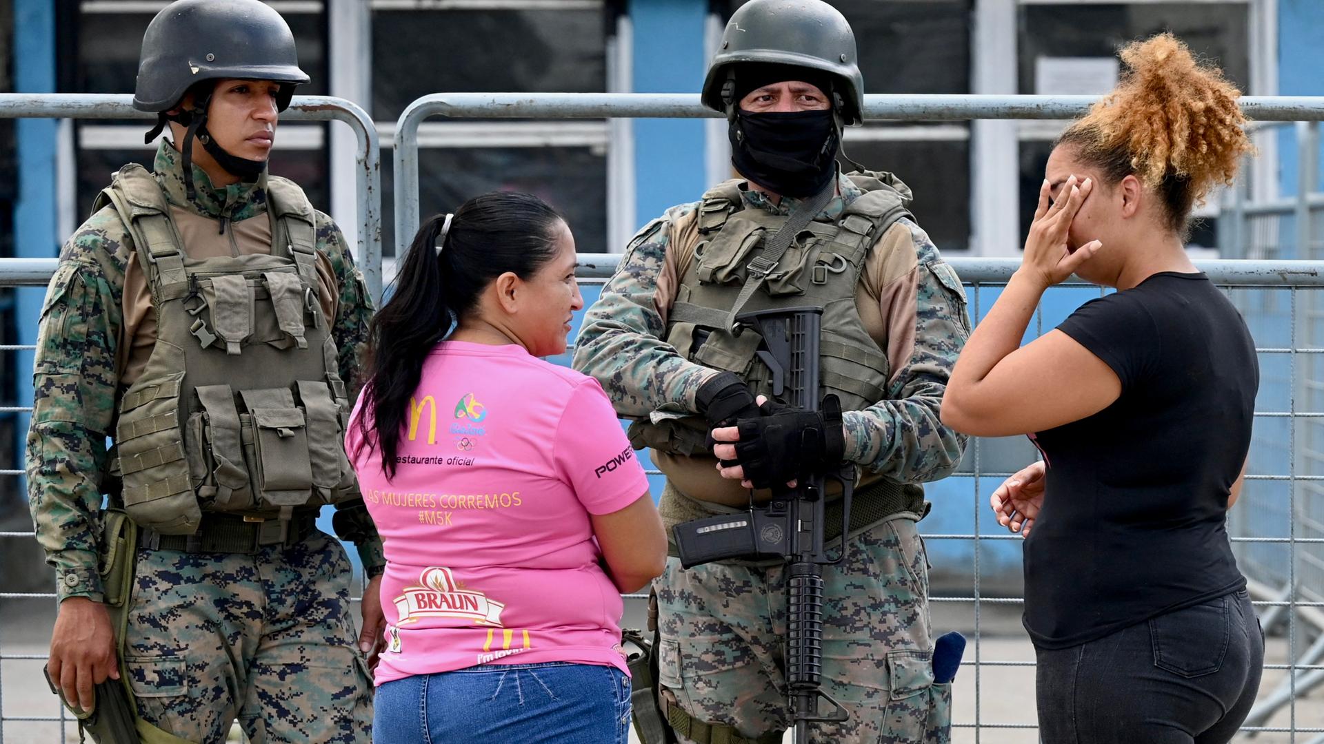 Zu sehen sind Angehörige von Gefangenen und zwei Soldaten vor einem Gefängnis nahe der Stadt Guayaquil in Ecuador.