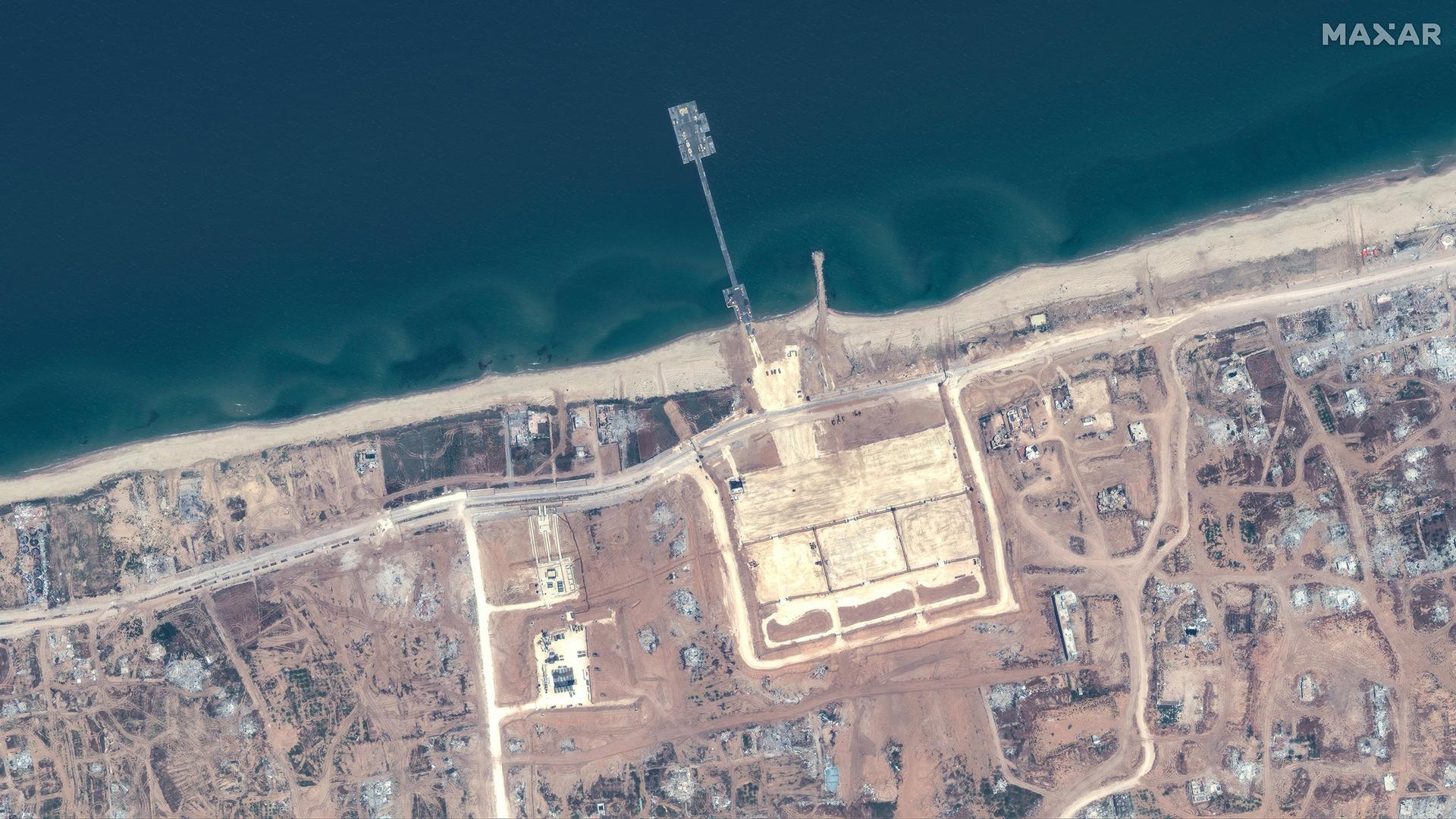 Ein Satellitenbild eines Küstenabschnitts des Gazastreifens, von dem ein Pier ins Mittelmeer ragt.