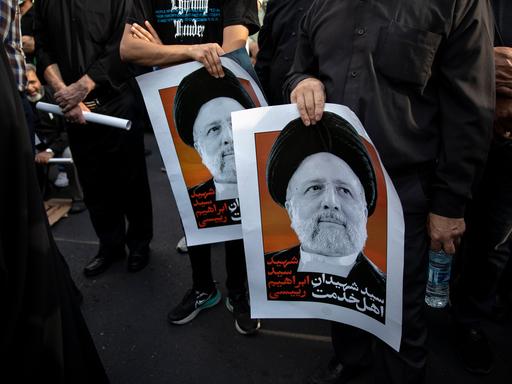 Menschen halten zwei Plakate mit dem Porträt des tödlich verunglückten iranischen Präsident Ebrahim Raisi.