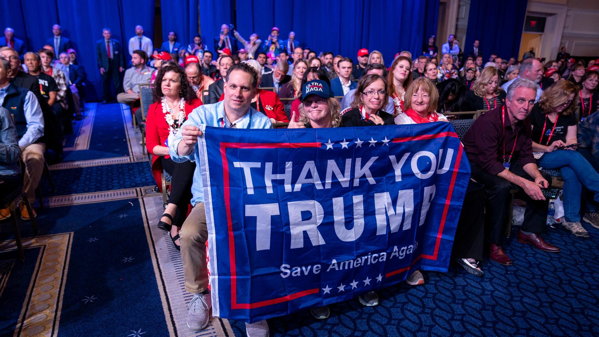 Unterstützer von Donald Trump halten ein Banner hoch. Darauf steht "Thank You Trump. Save America Again".