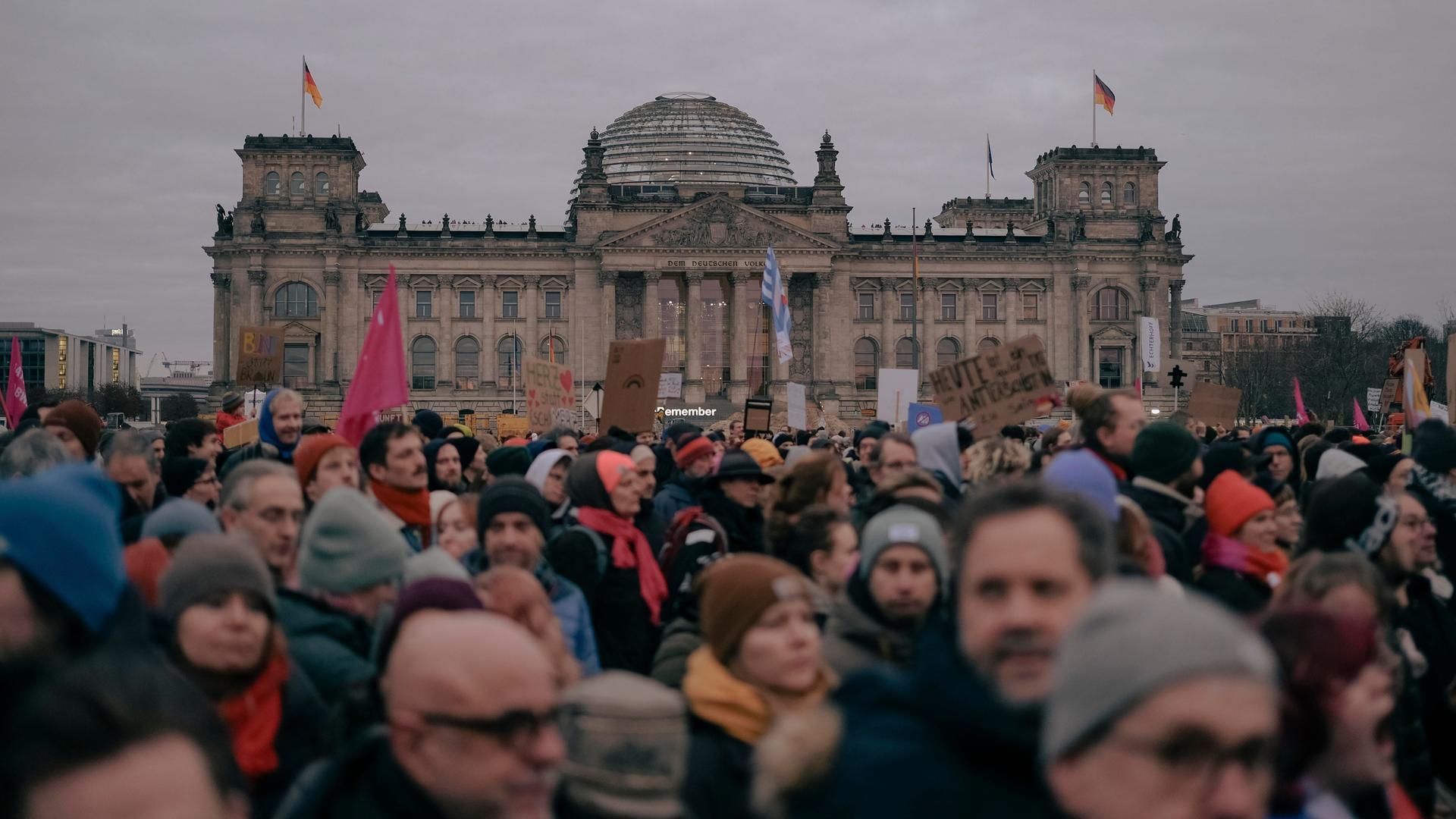 Vor dem Reichstagsgebäude in Berlin sind viele Menschen und demonstrieren. Es ist ein Protest gegen die Kooperation der CDU/CSU mit der AfD. 