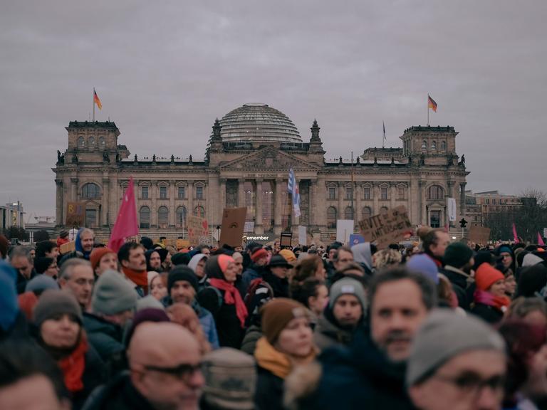 Vor dem Reichstagsgebäude in Berlin sind viele Menschen und demonstrieren. Es ist ein Protest gegen die Kooperation der CDU/CSU mit der AfD. 