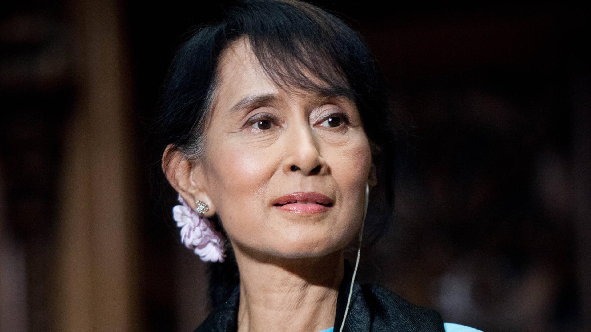 Porträt von Aung San Suu Kyi mit einem blauen Kleid und einem schwarzen Schaal.