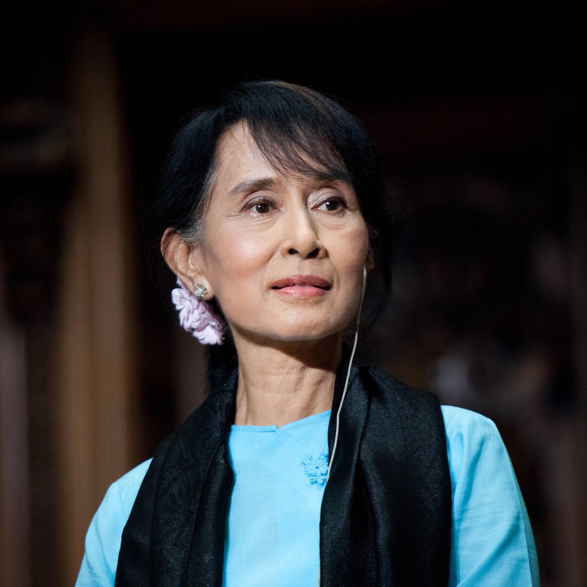 Porträt von Aung San Suu Kyi mit einem blauen Kleid und einem schwarzen Schaal.