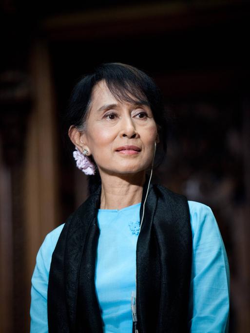 Porträt von Aung San Suu Kyi mit einem blauen Kleid und einem schwarzen Schaal.