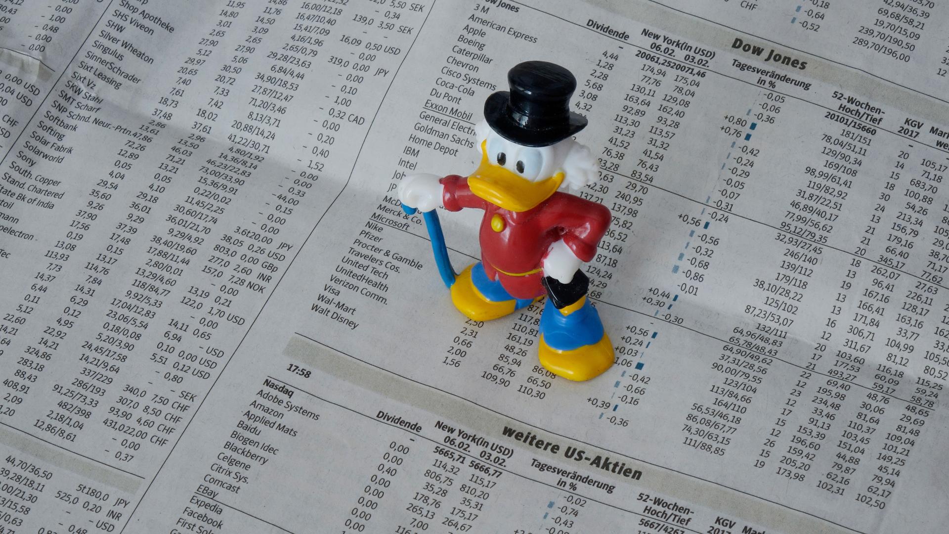 Eine Figur von Dagobert Duck steht auf der Börsenseite einer Zeitung.