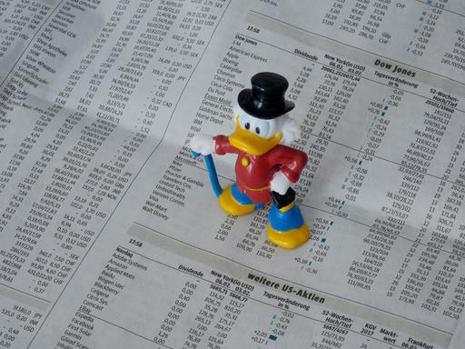 Eine Figur von Dagobert Duck steht auf der Börsenseite einer Zeitung.