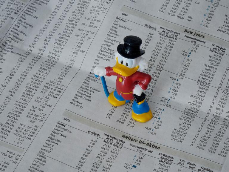 Eine Figur von Dagobert Duck steht auf der Börsenseite einer Zeitung.