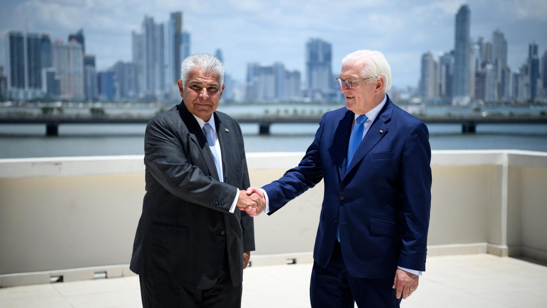 Panamas Präsident José Raul Mulino Quintero und Bundespräsident Frank-Walter Steinmeier schütteln sich die Hände. Sie stehen auf einer Terrasse, im Hintergrund ist die Skyline von Panama-Stadt zu sehen. Panamas Präsident José Raul Mulino Quintero und Bundespräsident Frank-Walter Steinmeier schütteln sich die Hände. Sie stehen auf einer Terrasse, im Hintergrund ist die Skyline von Panama-Stadt zu sehen.
