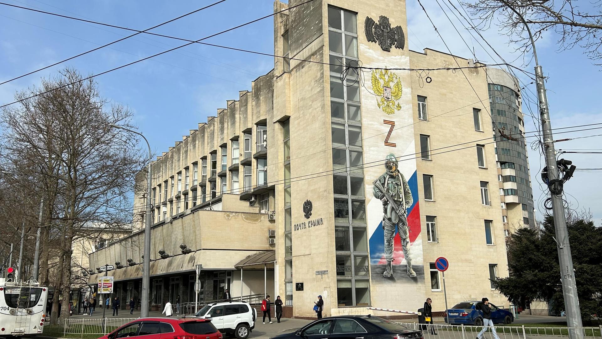 Ukraine, Simferopol: An der Fassade der Hauptpost im Zentrum der Hauptstadt der Schwarzmeer-Halbinsel Krim erinnert ein großes Wandbild an die "militärische Spezialoperation", wie Russland seinen Krieg gegen die Ukraine nennt. 