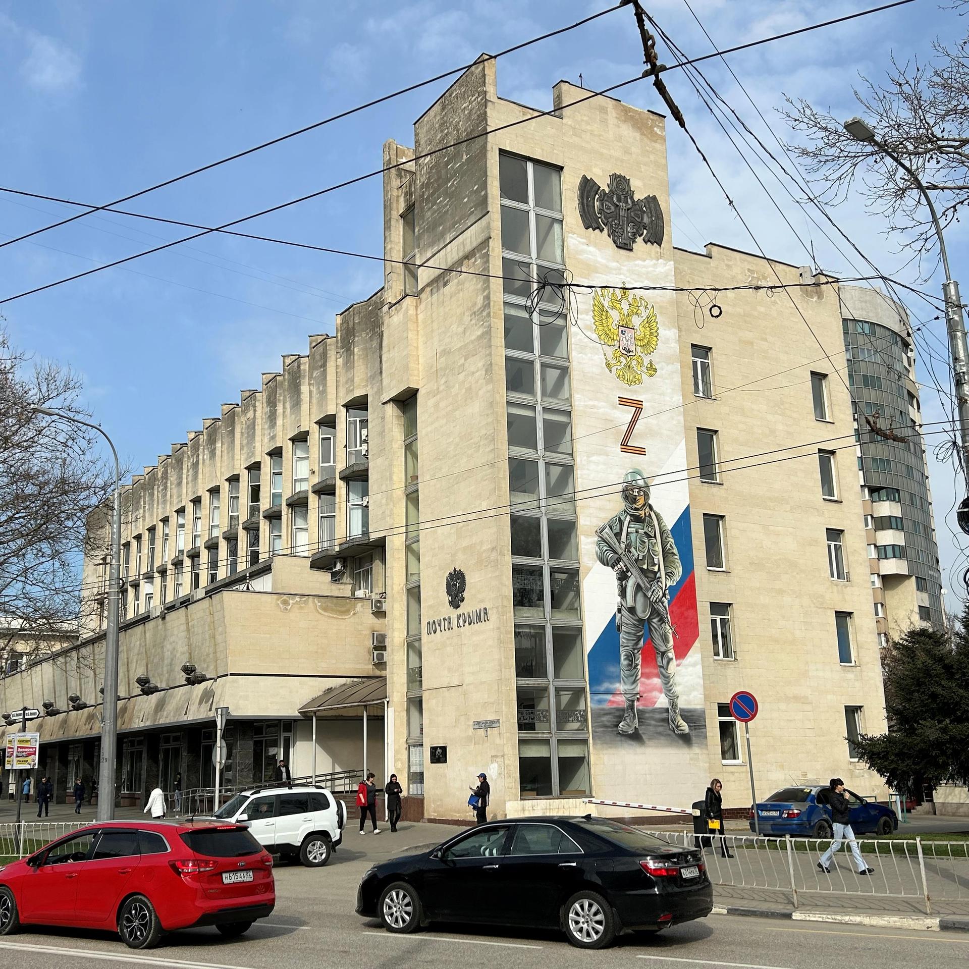Ukraine, Simferopol: An der Fassade der Hauptpost im Zentrum der Hauptstadt der Schwarzmeer-Halbinsel Krim erinnert ein großes Wandbild an die "militärische Spezialoperation", wie Russland seinen Krieg gegen die Ukraine nennt. 