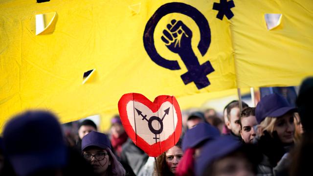 Demonstrantinnen gehen in Berlin für den internationalen Frauentag auf die Straße. Sie halten Transparente und Schilder mit verfremdetem Venussymbol.