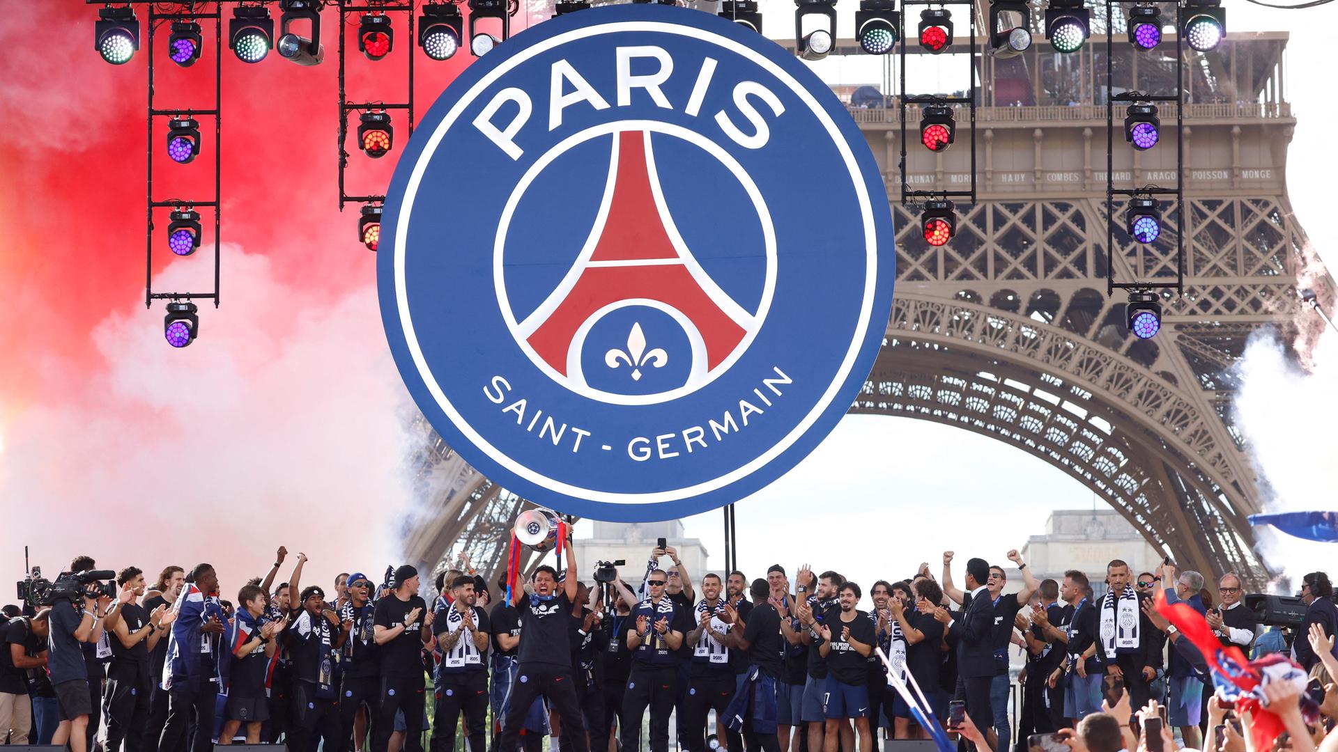 Auf einer Bühne vor dem Eiffelturm mit einem großen Vereinslogo lässt sich die Mannschaft von Champions-League-Sieger PSG feiern. Auf einer Bühne vor dem Eiffelturm mit einem großen Vereinslogo lässt sich die Mannschaft von Champions-League-Sieger PSG feiern.