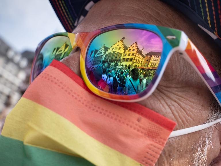 In einer Sonnenbrille in Regenbogenfarben spiegelt sich beim  Christopher Street Day Frankfurt 2021 der Römer, das historische Rathaus der Stadt