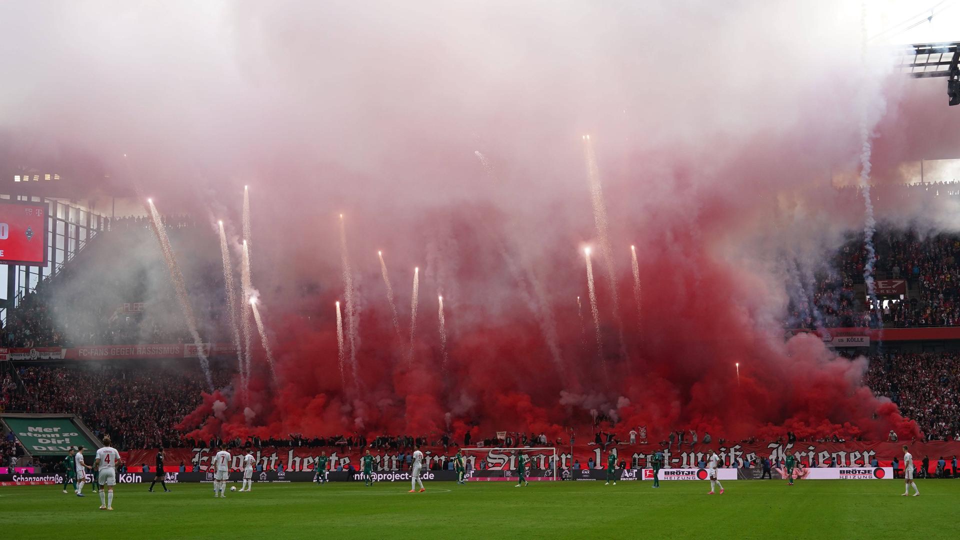 Das Foto zeigt eine Aufnahme im Kölner Fußballstadion. Fans haben ein Feuerwerk gezündet. Rote Rauschschwaden behindern die Sicht.