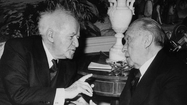 David Ben Gurion und Konrad Adenauer sitzen an einem Salontisch und reden miteinander.